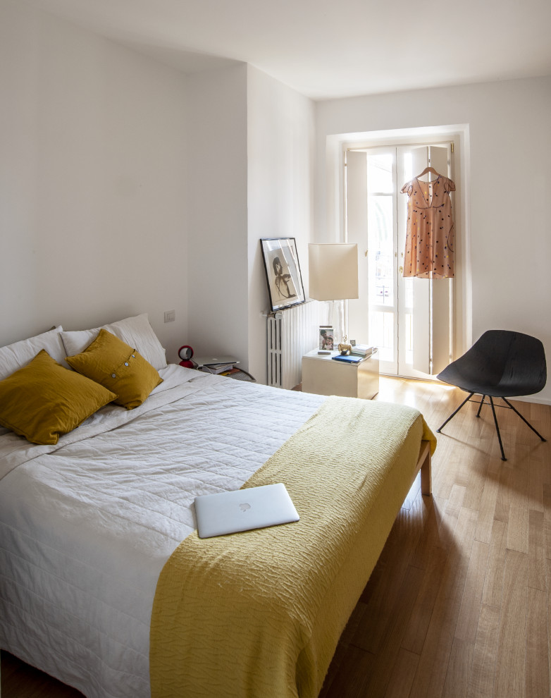 Ispirazione per una camera da letto contemporanea con pareti bianche, pavimento in legno massello medio e pavimento marrone