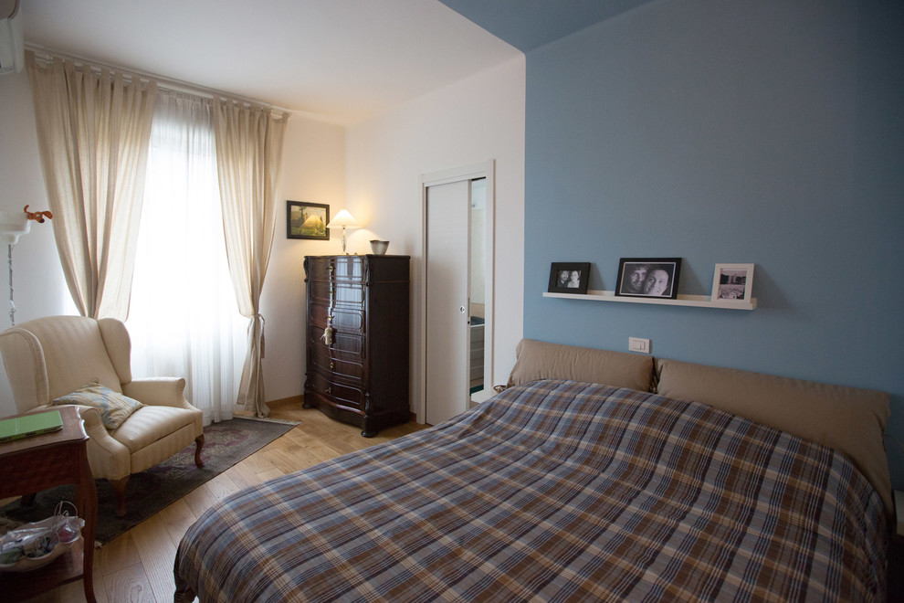 Exemple d'une petite chambre chic avec un mur bleu, un sol en bois brun et un sol marron.