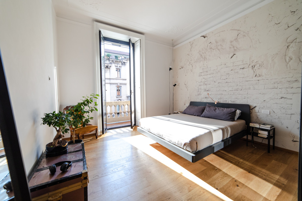 ミラノにある広いコンテンポラリースタイルのおしゃれな主寝室 (白い壁、茶色い床、無垢フローリング、壁紙) のインテリア