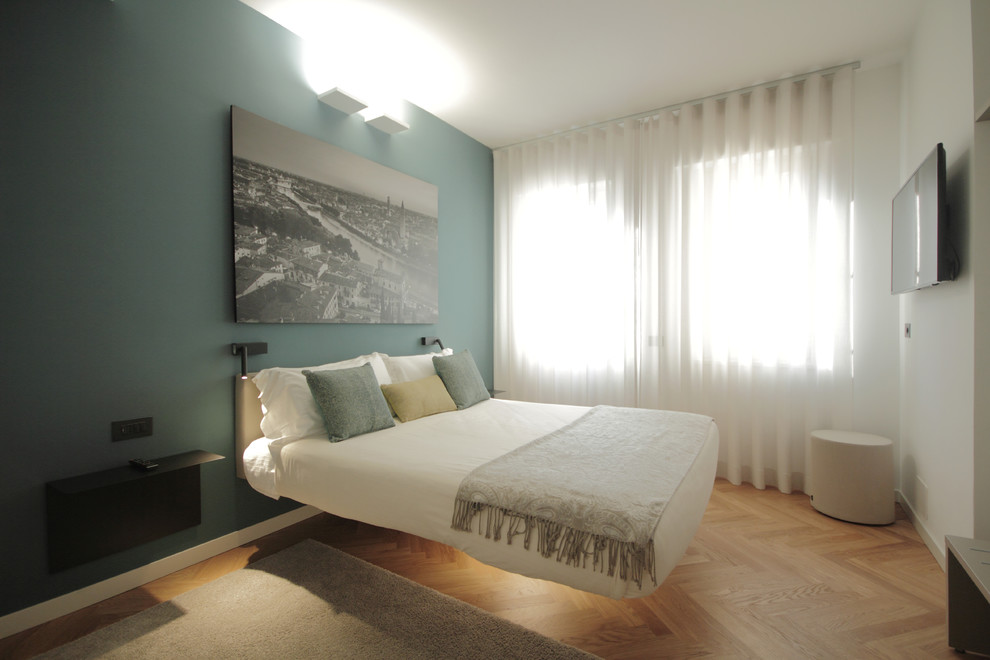 Diseño de dormitorio televisión contemporáneo con paredes verdes, suelo de madera en tonos medios y suelo marrón