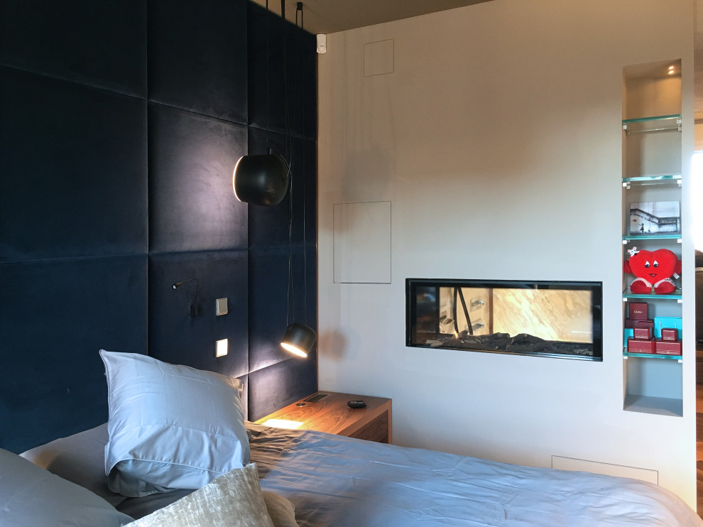 This is an example of a medium sized contemporary master bedroom in Milan with a two-sided fireplace and a plastered fireplace surround.