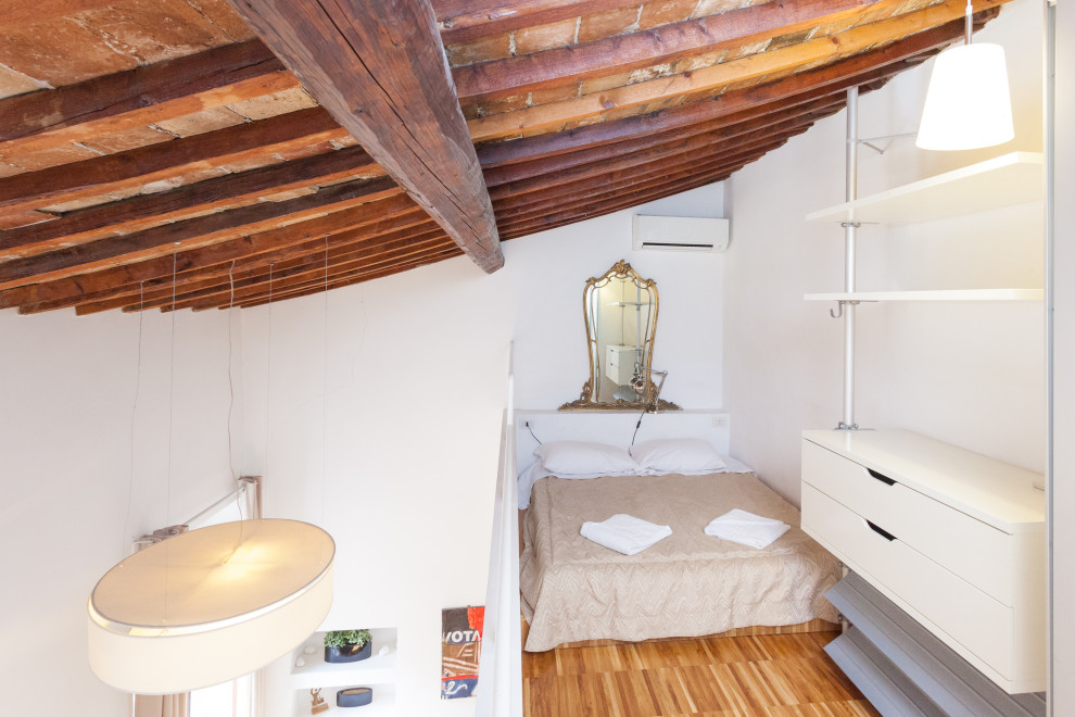 Idee per una camera da letto stile loft design con pareti bianche, pavimento in legno massello medio, pavimento marrone, travi a vista e soffitto a volta