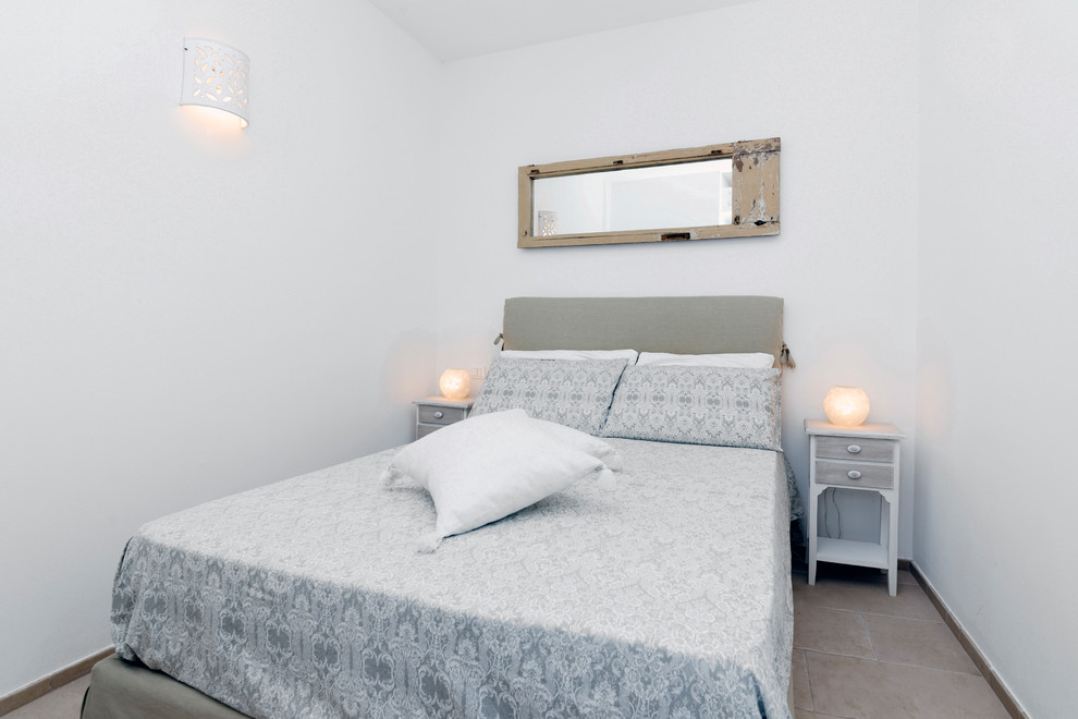 Esempio di una camera degli ospiti mediterranea con pareti bianche e pavimento beige