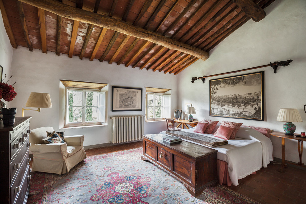 Idée de décoration pour une grande chambre parentale champêtre avec un mur blanc, tomettes au sol et un sol rouge.