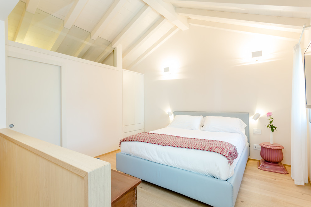 Modelo de dormitorio principal mediterráneo con paredes blancas, suelo de madera clara y suelo beige