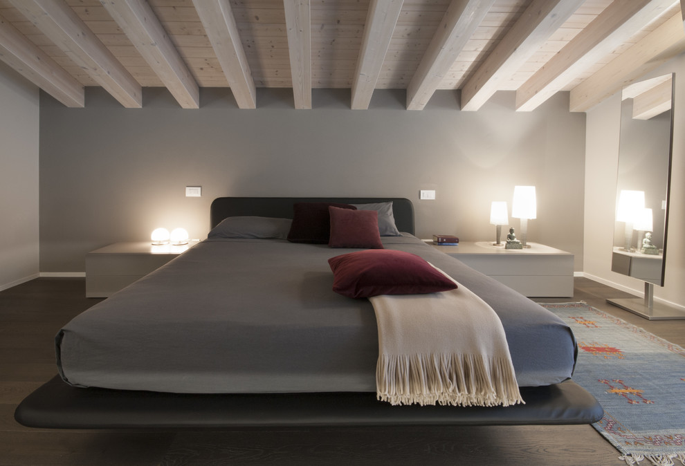 Mittelgroßes Modernes Hauptschlafzimmer ohne Kamin mit grauer Wandfarbe, dunklem Holzboden und braunem Boden in Venedig