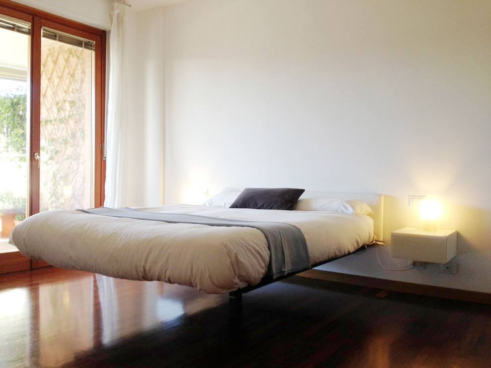Esempio di una camera matrimoniale minimal di medie dimensioni con pareti bianche e pavimento in legno massello medio