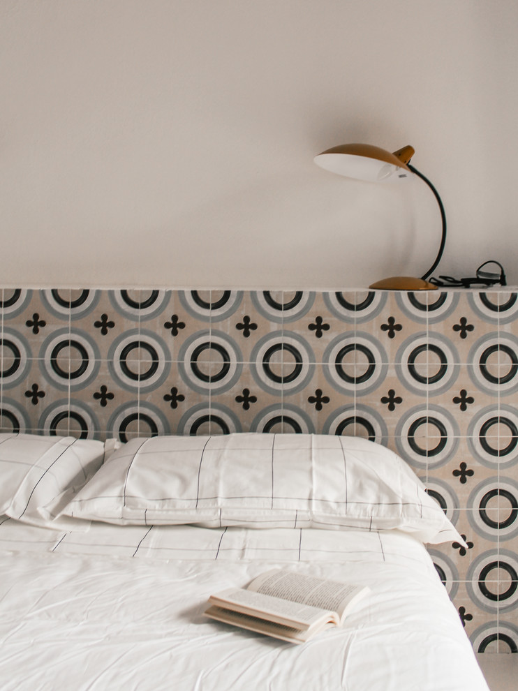 Ispirazione per una camera da letto stile loft mediterranea di medie dimensioni con pareti bianche, pavimento in cemento e pavimento grigio