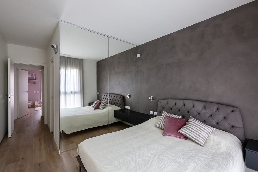 Réalisation d'une chambre parentale minimaliste de taille moyenne avec un mur gris et parquet clair.
