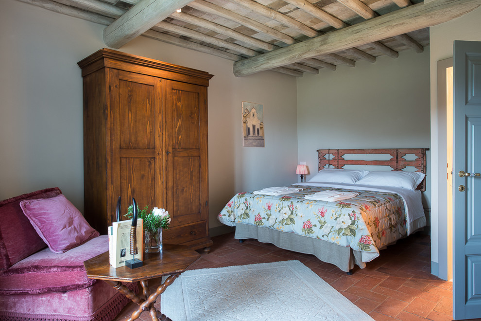 Ejemplo de dormitorio principal campestre con paredes blancas y suelo de baldosas de terracota