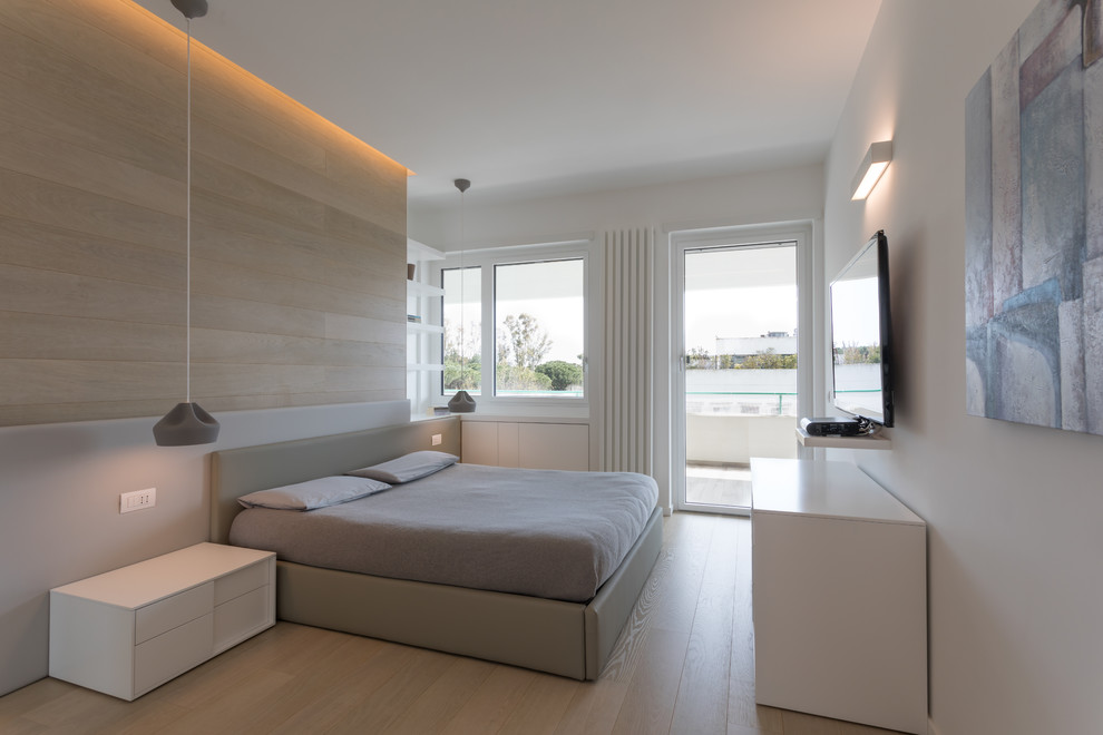 Immagine di una camera da letto minimal con pareti bianche, parquet chiaro, pavimento beige e TV