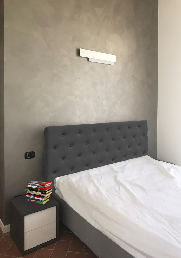 ミラノにある小さなコンテンポラリースタイルのおしゃれな主寝室 (グレーの壁、テラコッタタイルの床、茶色い床)