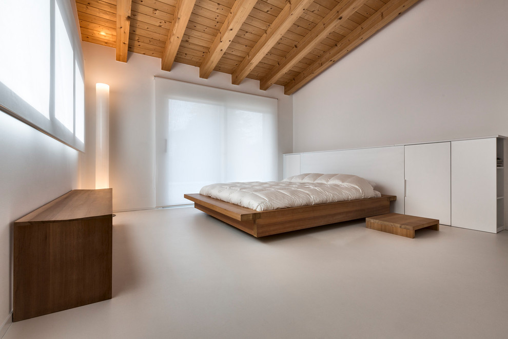 Cette image montre une grande chambre parentale minimaliste avec un mur blanc, aucune cheminée et un sol gris.