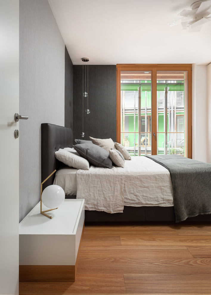 Idée de décoration pour une chambre parentale minimaliste de taille moyenne avec un sol en bois brun, un mur gris et un sol marron.