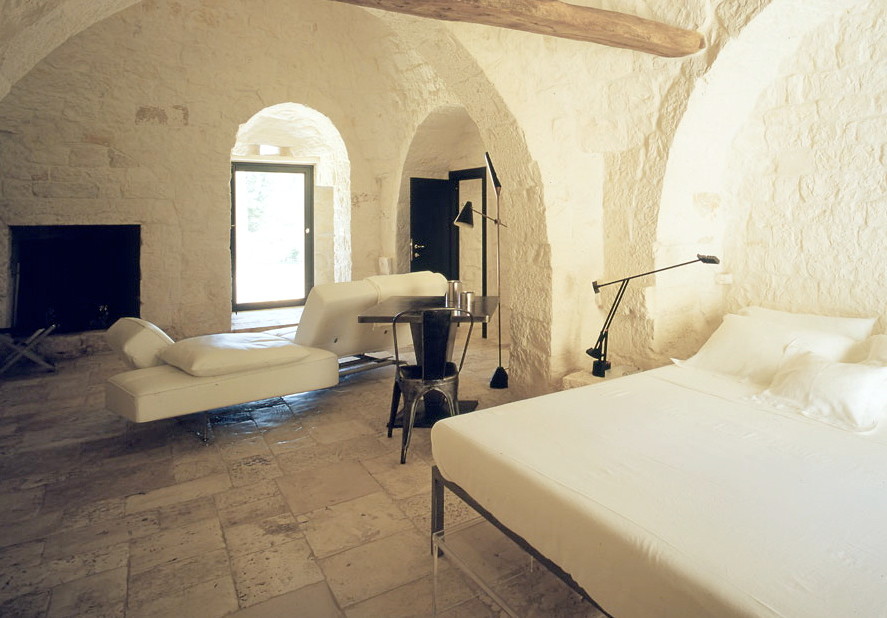 バーリにある広いコンテンポラリースタイルのおしゃれな主寝室 (白い壁、ライムストーンの床、標準型暖炉、石材の暖炉まわり、ベージュの床) のレイアウト
