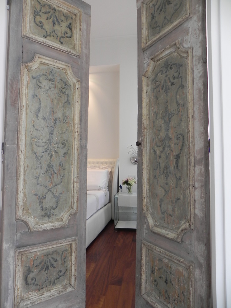 Shabby-Style Hauptschlafzimmer mit weißer Wandfarbe und dunklem Holzboden in Mailand
