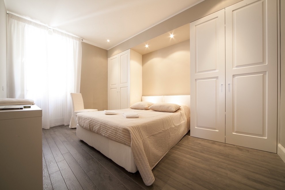 Imagen de dormitorio principal actual con suelo de madera oscura, paredes beige y suelo marrón