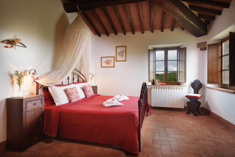 Пример оригинального дизайна: хозяйская спальня среднего размера в стиле кантри с белыми стенами, полом из терракотовой плитки и оранжевым полом