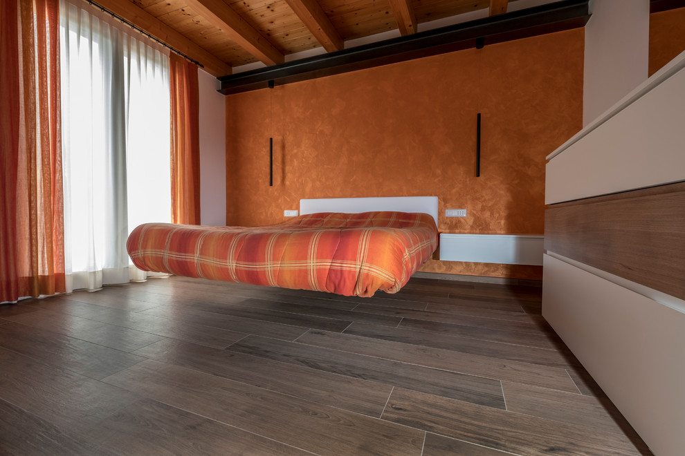 Идея дизайна: хозяйская спальня среднего размера в стиле модернизм с оранжевыми стенами, деревянным полом и коричневым полом