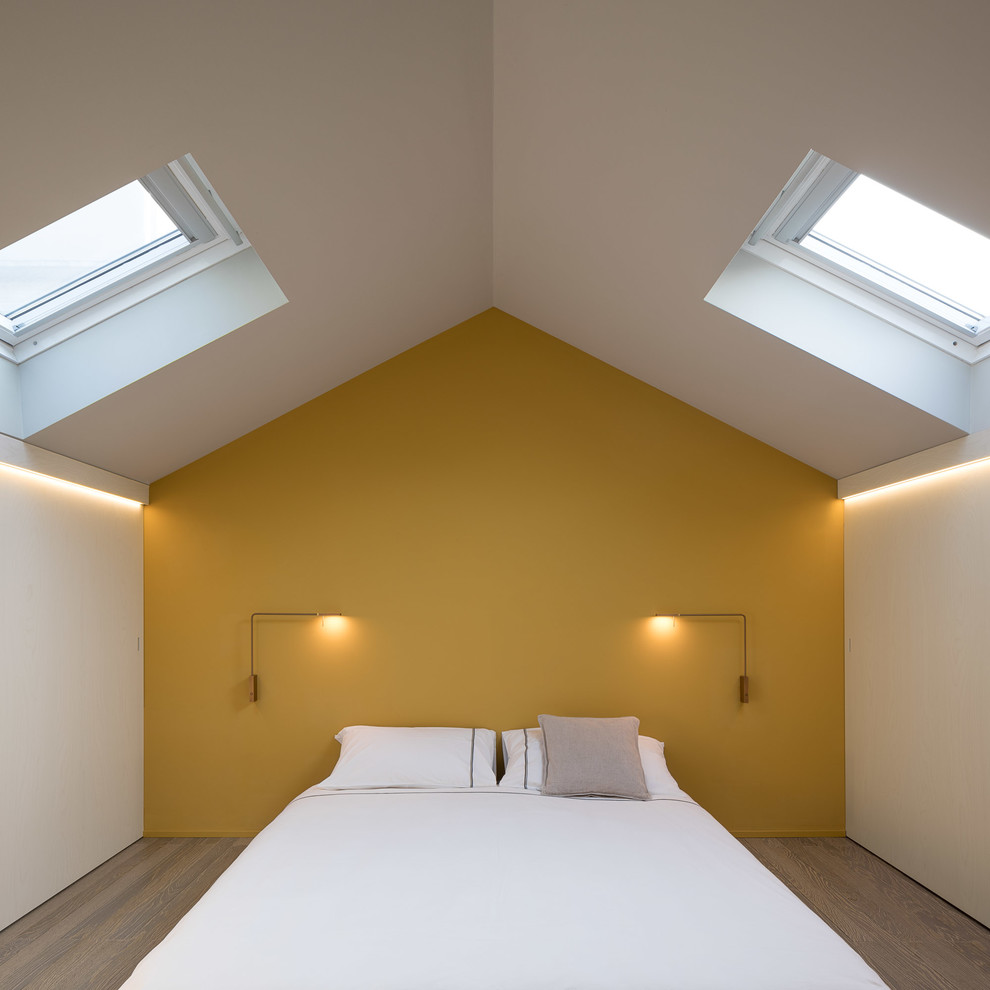 Modernes Hauptschlafzimmer mit braunem Holzboden, braunem Boden und gelber Wandfarbe in Mailand