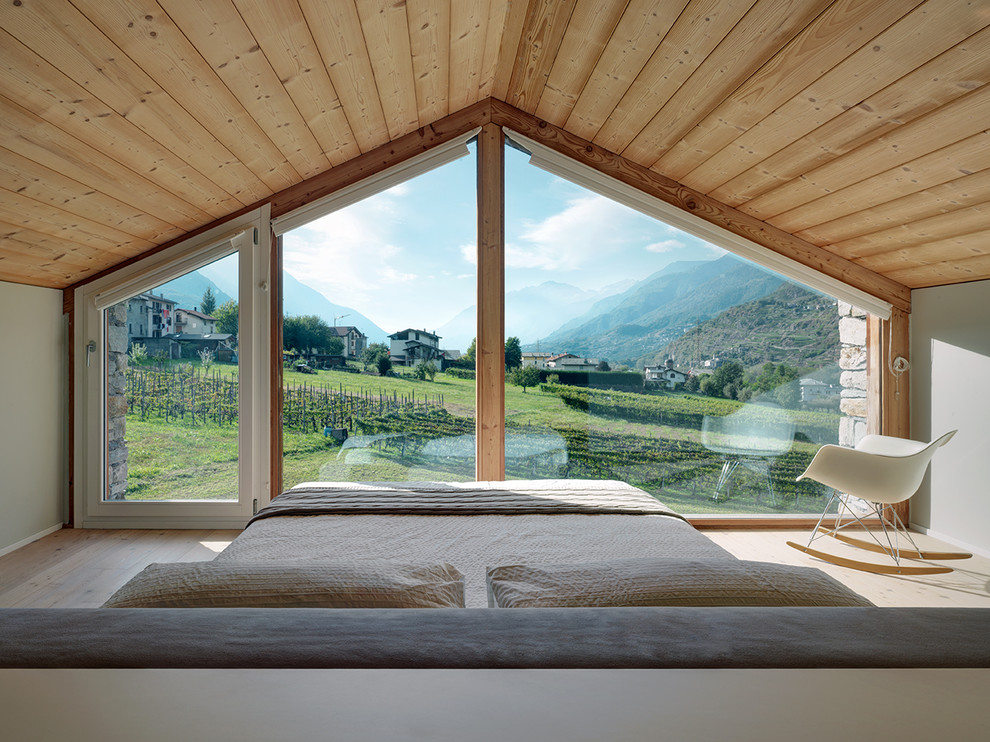 Modelo de dormitorio actual sin chimenea con paredes grises, suelo de madera clara y suelo beige