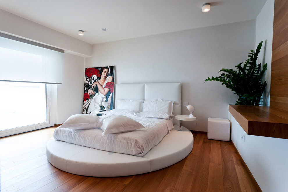 Modern bedroom in Venice with white walls, medium hardwood flooring and brown floors.