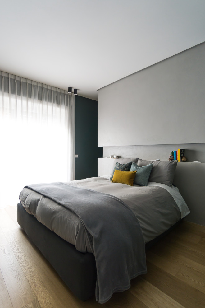 Mittelgroßes Nordisches Hauptschlafzimmer mit grauer Wandfarbe und hellem Holzboden
