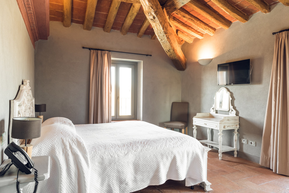 Стильный дизайн: хозяйская спальня на мансарде в стиле кантри с серыми стенами и полом из терракотовой плитки - последний тренд
