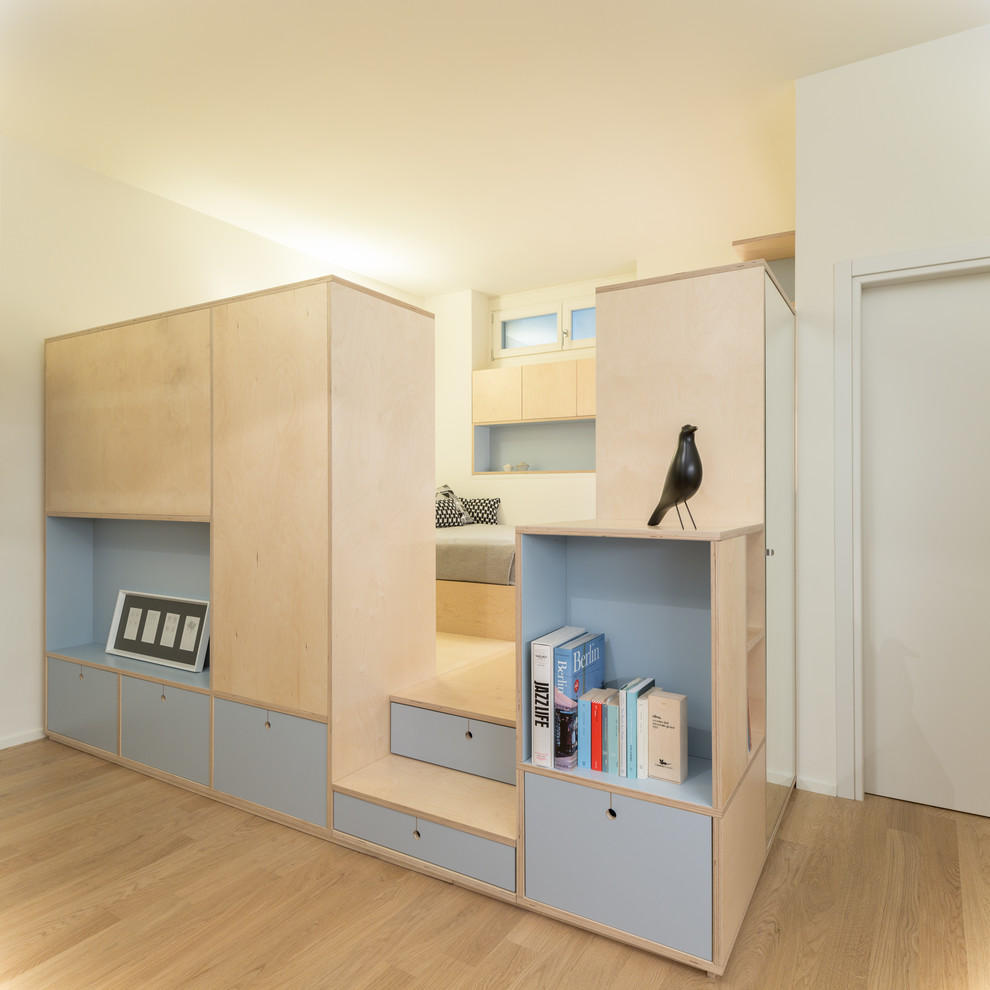 Imagen de dormitorio tipo loft actual de tamaño medio con paredes blancas, suelo de madera clara y suelo beige