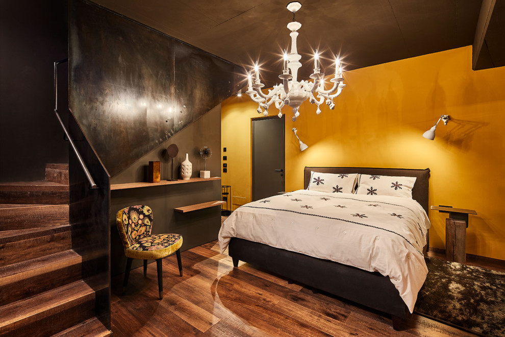 Esempio di una camera da letto design con pareti gialle, pavimento in legno massello medio e pavimento marrone