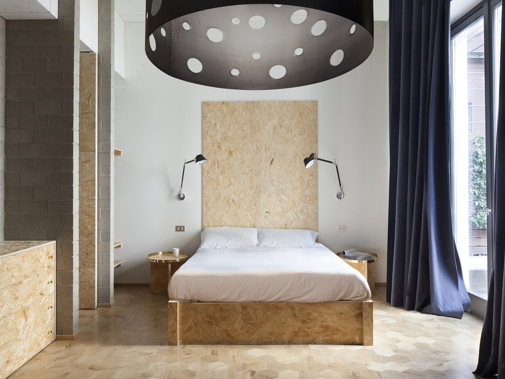 Großes Industrial Hauptschlafzimmer mit weißer Wandfarbe und hellem Holzboden in Mailand