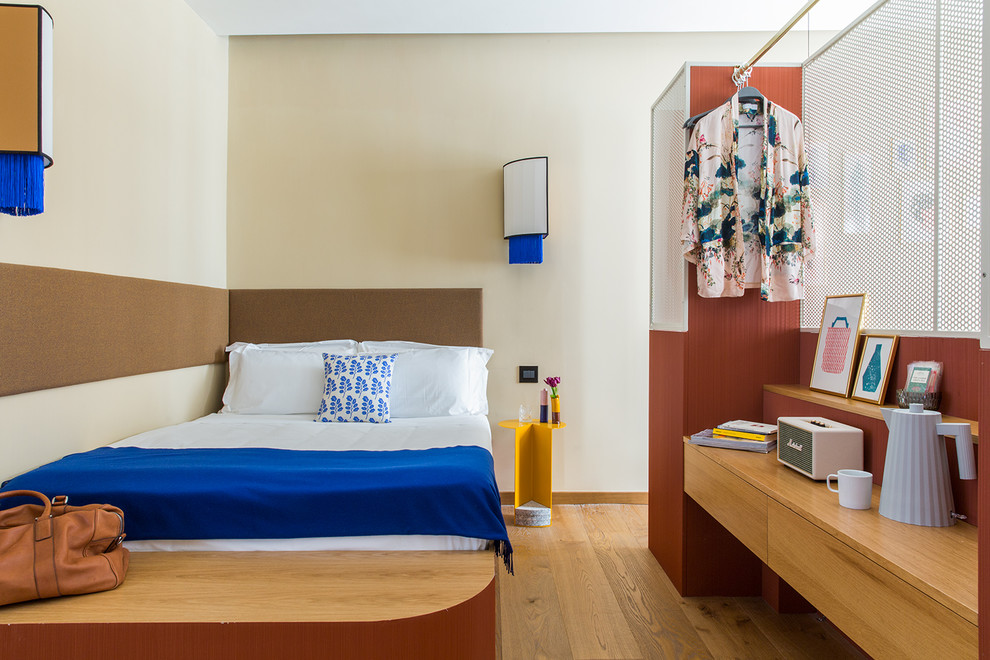 Modelo de dormitorio actual grande con paredes beige, suelo de madera en tonos medios y suelo marrón