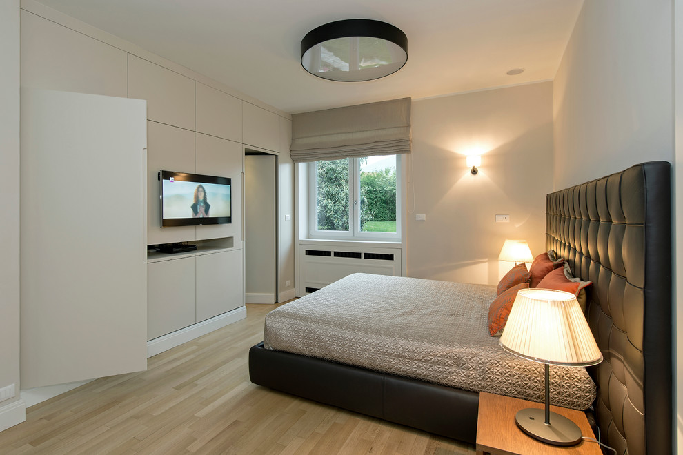 Imagen de dormitorio principal actual grande con suelo de madera en tonos medios y paredes blancas