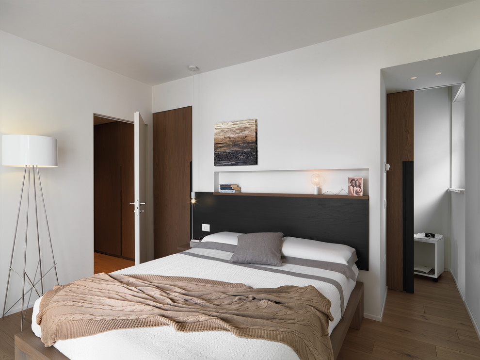 Foto di una camera da letto design con pareti bianche, parquet chiaro e pavimento marrone