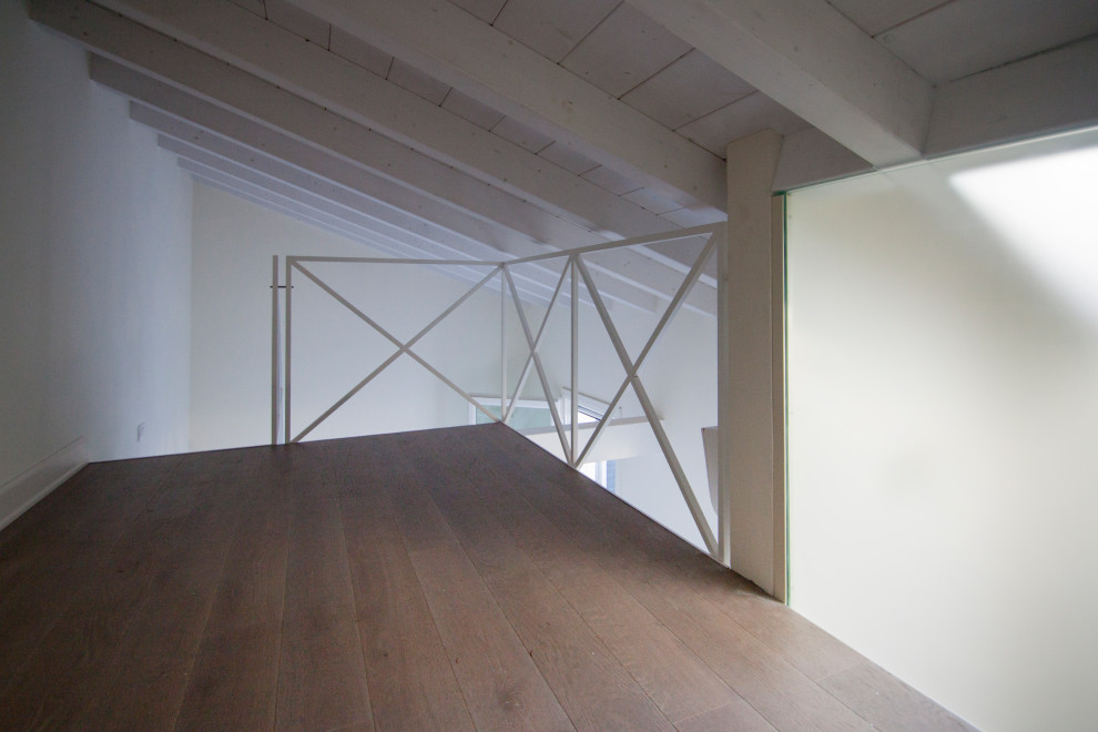 Immagine di una piccola camera da letto contemporanea con pareti beige, pavimento in legno massello medio e pavimento beige
