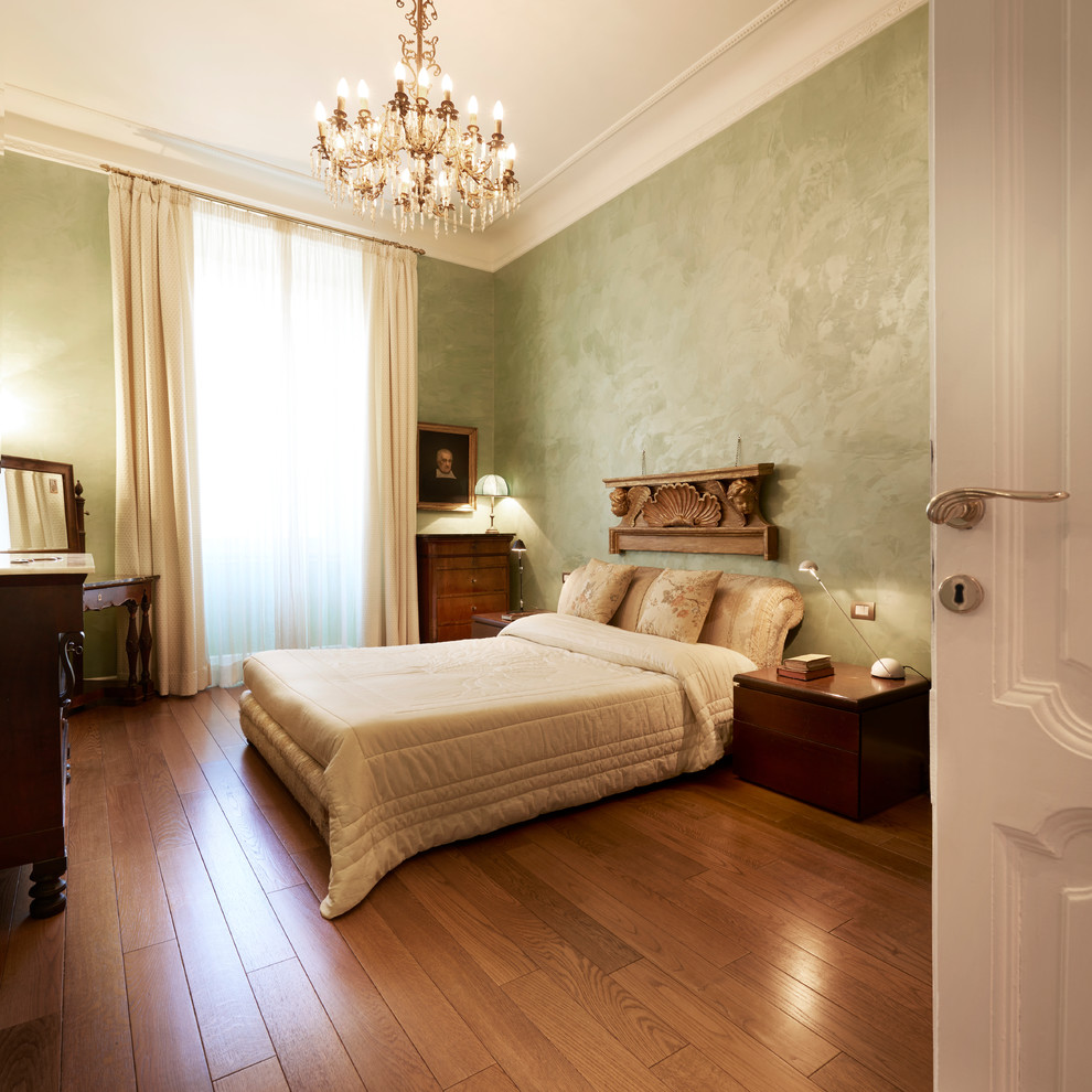 Immagine di una grande camera matrimoniale minimalista con pareti verdi e pavimento in legno massello medio