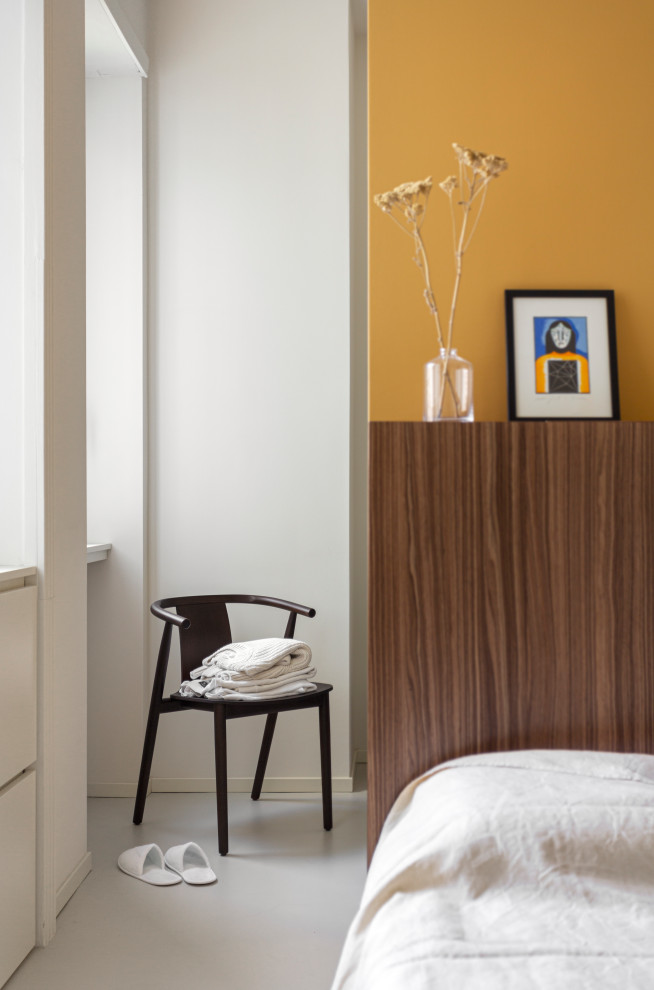 Modelo de dormitorio principal contemporáneo pequeño con paredes amarillas, suelo de madera en tonos medios y boiserie