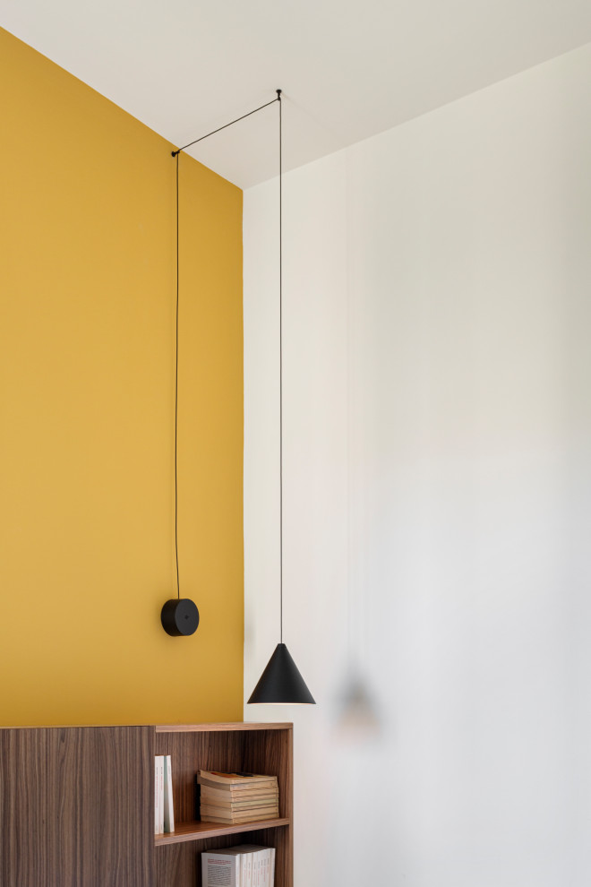 Kleines Modernes Hauptschlafzimmer mit gelber Wandfarbe, braunem Holzboden und vertäfelten Wänden in Mailand