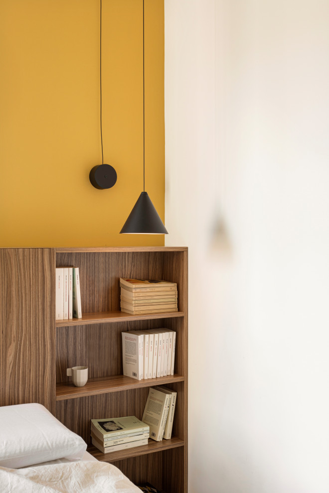 Ejemplo de dormitorio principal actual pequeño con paredes amarillas, suelo de madera en tonos medios y boiserie