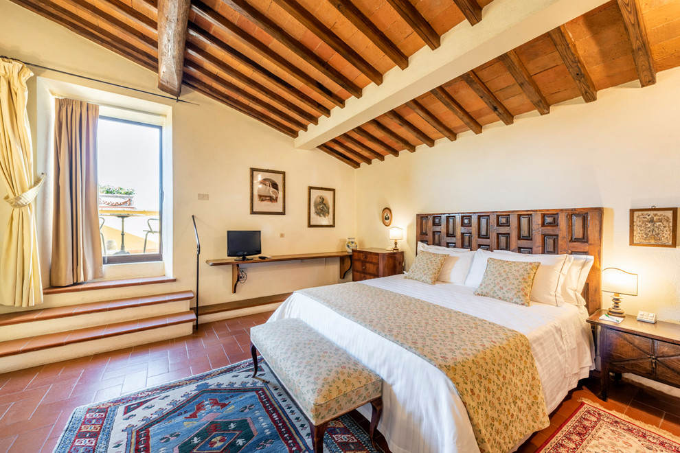 Ejemplo de dormitorio principal mediterráneo con paredes beige y suelo rojo