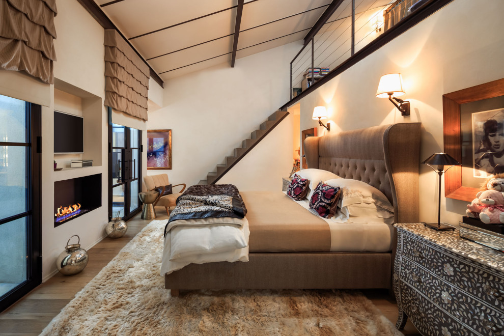 На фото: спальня на мансарде в средиземноморском стиле с белыми стенами, паркетным полом среднего тона, коричневым полом и сводчатым потолком с