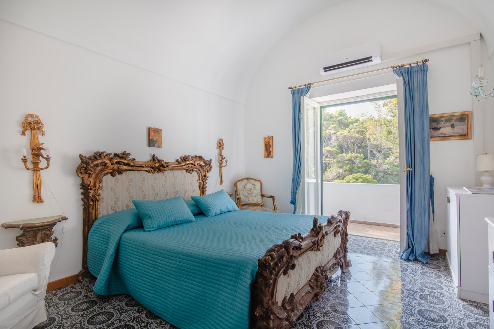 Immagine di una camera da letto mediterranea con pareti bianche, pavimento grigio e soffitto a volta