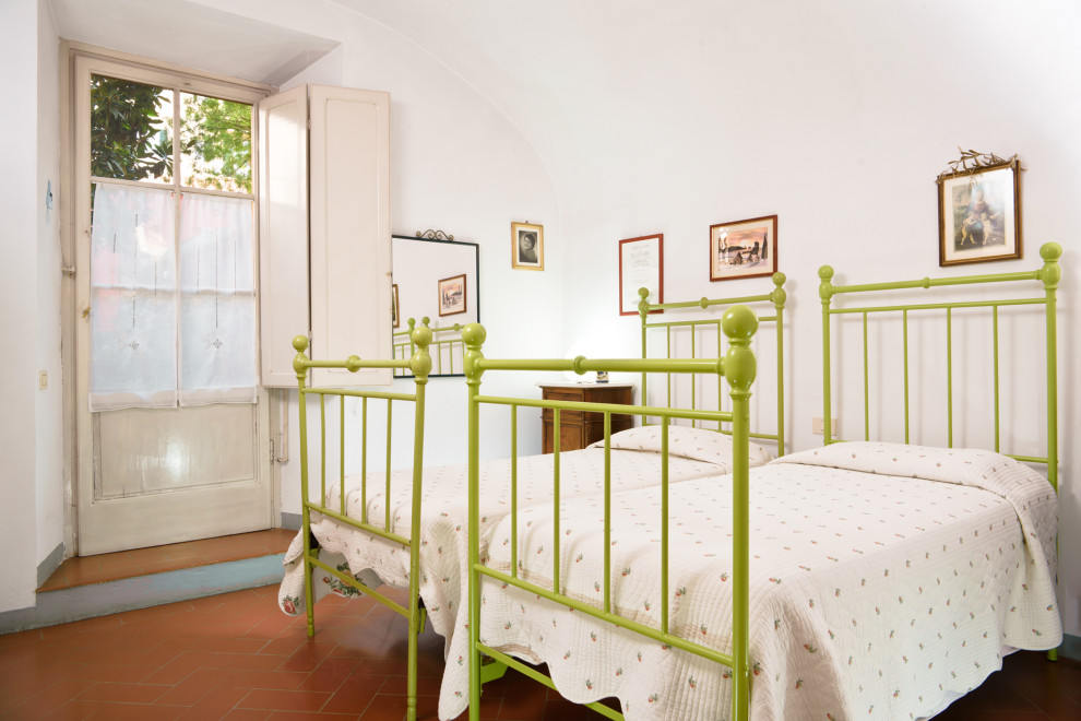 На фото: маленькая гостевая спальня (комната для гостей) в стиле шебби-шик с белыми стенами, полом из терракотовой плитки, оранжевым полом и сводчатым потолком для на участке и в саду