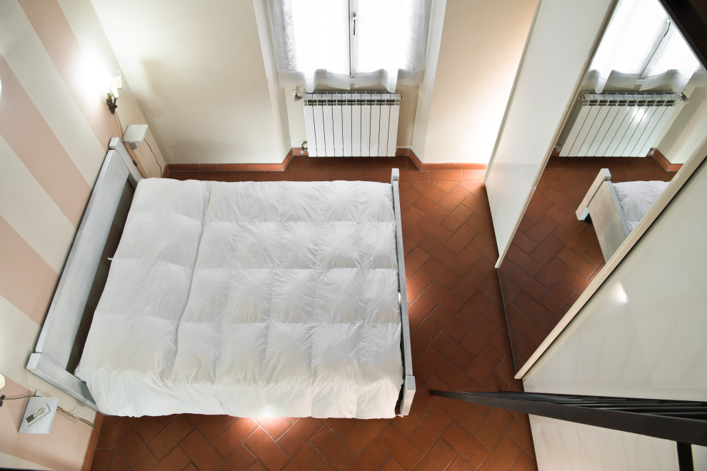 Ejemplo de dormitorio principal contemporáneo pequeño con paredes beige, suelo de baldosas de terracota y suelo naranja