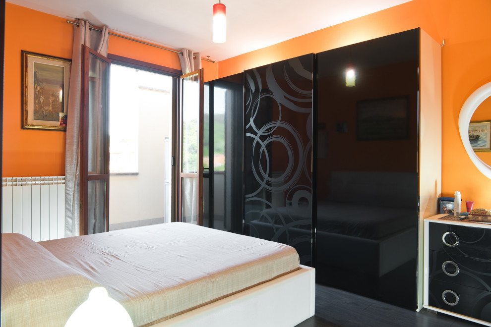 Cette image montre une petite chambre parentale design avec un mur orange, parquet foncé et un sol marron.