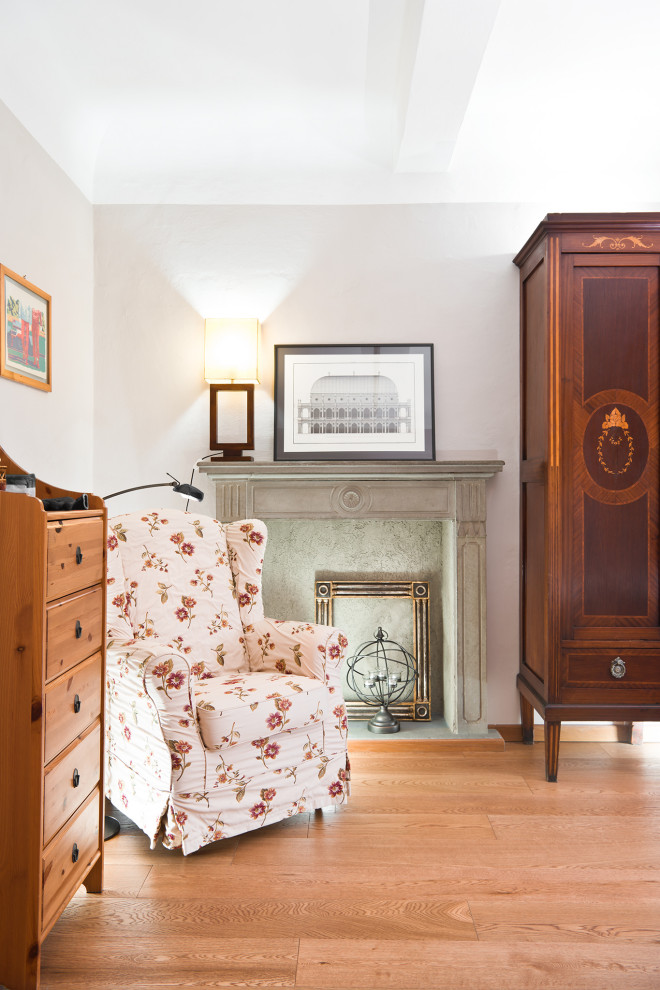 Immagine di una piccola camera matrimoniale stile shabby con pareti bianche, parquet chiaro, camino classico, cornice del camino in pietra e pavimento marrone