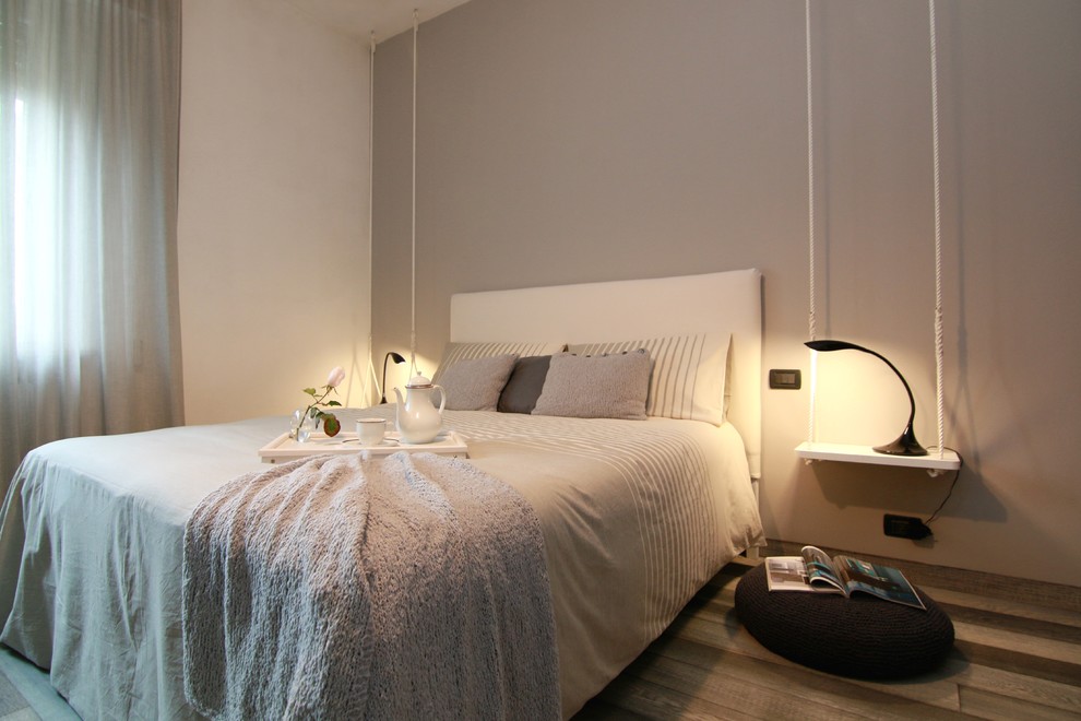 Ejemplo de dormitorio principal minimalista de tamaño medio con paredes grises y suelo de madera pintada
