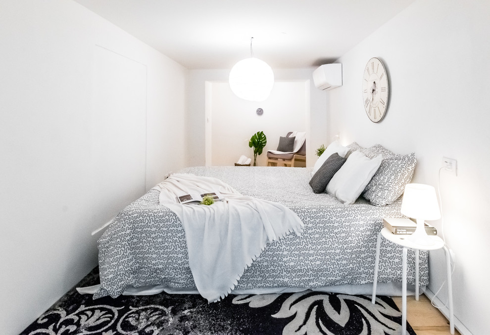 Immagine di una camera da letto nordica di medie dimensioni con pareti bianche, parquet chiaro, nessun camino e pavimento marrone