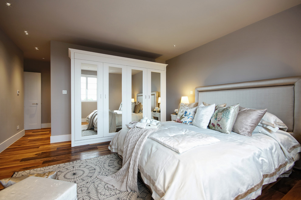 Example of a transitional medium tone wood floor bedroom design in London with gray walls