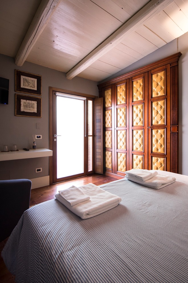 Ejemplo de habitación de invitados actual de tamaño medio con paredes grises y suelo de madera en tonos medios